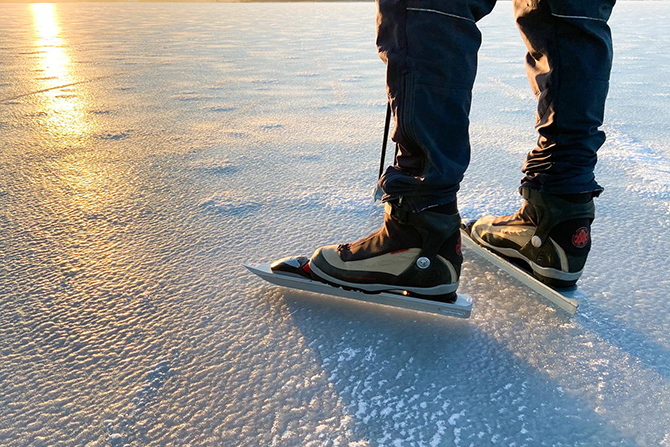 Närbild på is och skridskoåkares ben