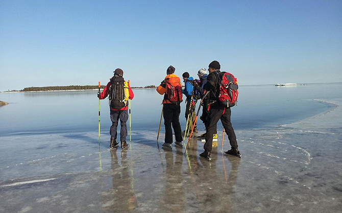 En grupp skridskoåkare blickar ut över spegelblank is